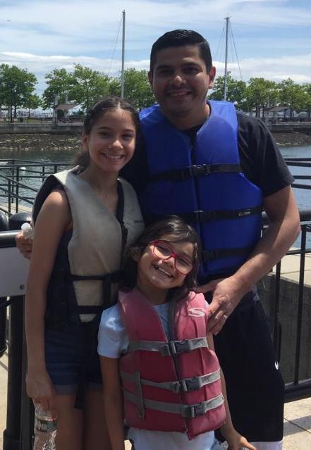 Father and daughters smiling in front of a river